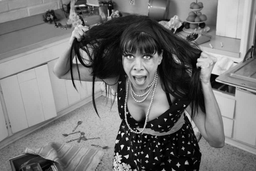 Desperate housewife pulling her hair in a messy kitchen