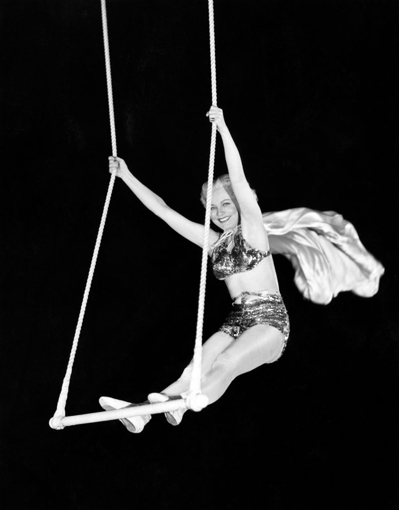 Portrait of a female circus performer performing on a trapeze bar
